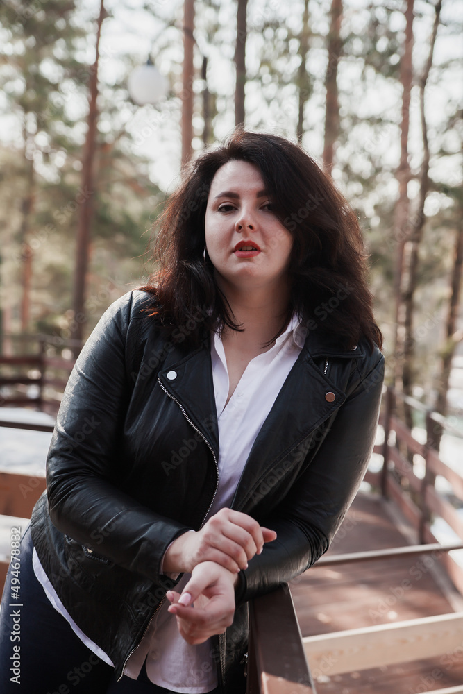 Young stylish woman wearing leather jacket walking in park. Young stylish woman wearing leather jacket walking in park.