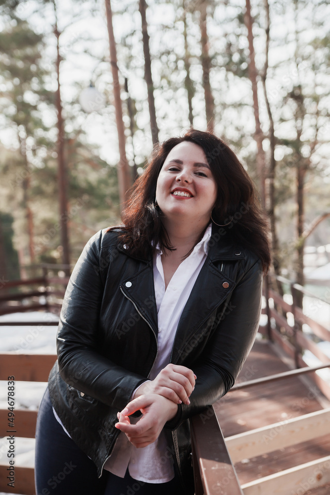 Young stylish woman wearing leather jacket walking in park. Young stylish woman wearing leather jacket walking in park.