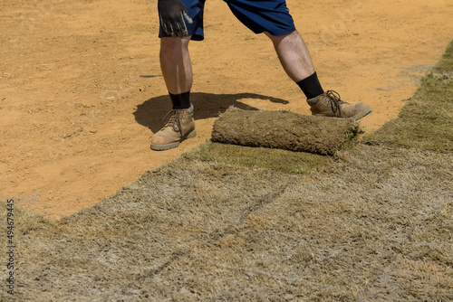 Applying rolled green grass with laying sod for new lawn