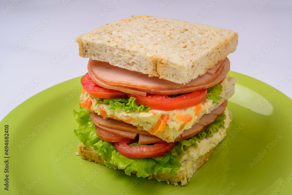 Big sandwich with smoked ham, with lettuce and tomato on green plate. Fast food. Big sandwich with smoked ham, with lettuce and tomato on green plate. Fast food.