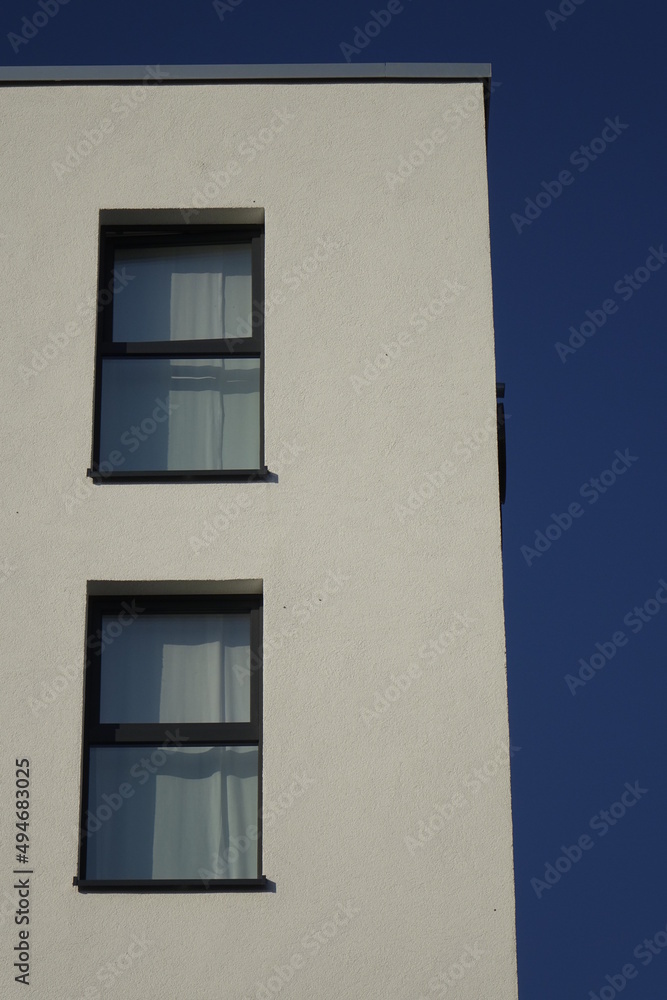 Upper right corner of white house wall with two windows, clear blue sky, use: copy space, texture, background (vertical), Kaiserslautern, RLP, Germany Upper right corner of white house wall with two windows, clear blue sky, use: copy space, texture, background (vertical), Kaiserslautern, RLP, Germany