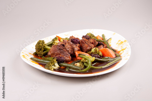 duck magret with vegetables on white plate isolated angle view