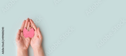 World Thyroid Day. Women's hands hold a paper form of the thyroid gland on a blue background. Problems with thyroid. Polycystic disease. World cancer day. copy space. banner photo