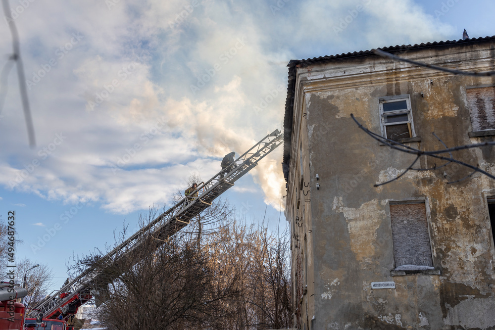 Firefighter works on boom of fire engine. Fireman on sky background. Burning old building in the historic center..Rescuers on a retractable ladder in the smoke. Firefighter works on boom of fire engine. Fireman on sky background. Burning old building in the historic center..Rescuers on a retractable ladder in the smoke.