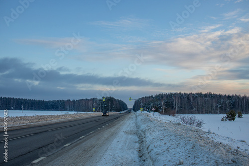 Winter evening landscape, road in the foreground. Sunset sky over the horizon.
