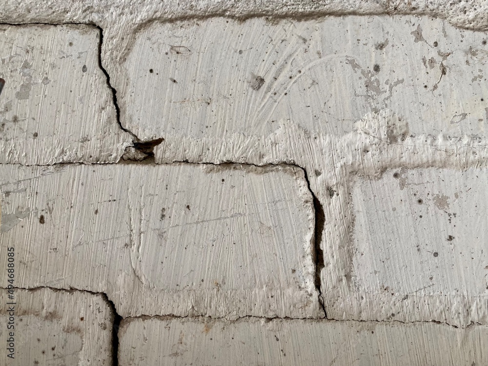Fototapeta premium an old white brick wall with a crack