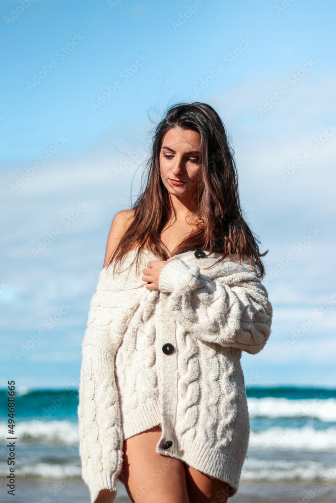 Beautiful and shy brunette woman looking down on the beach with ocean background Beautiful and shy brunette woman looking down on the beach with ocean background