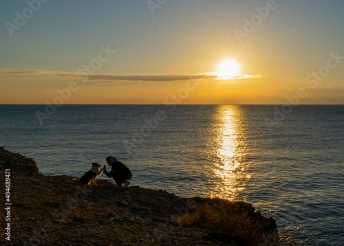 Chico con su perro en la playa mirando el amanecer