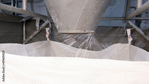 White hard grinded plastic comes out of the cyclone of the machine by pneumatic transport into the big bag. concept of recyclable materials, plastic recycling, pellet production plants photo