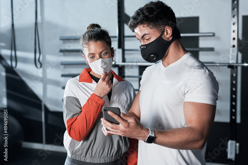 The stats will continue to rise if we dont stay safe. Shot of two sporty people looking at something on a cellphone together in a gym.