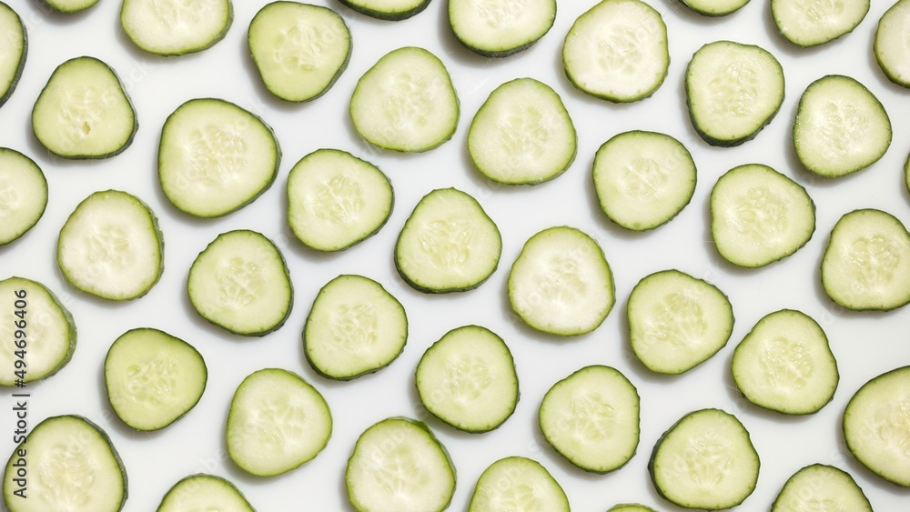 Wide shot of cucumber slices arranged in lines on white background | skin care background, body wash commercial Wide shot of cucumber slices arranged in lines on white background | skin care background, body wash commercial