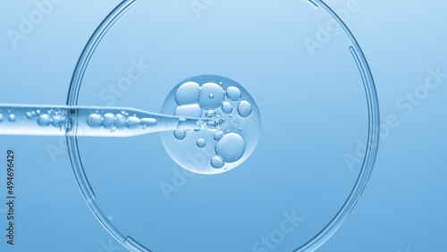 Close up view macro shot of gel with different sized bubbles comes out from lab dropper into petri dish on blue background | Abstract face care gel with hyaluronic acid mixing concept photo
