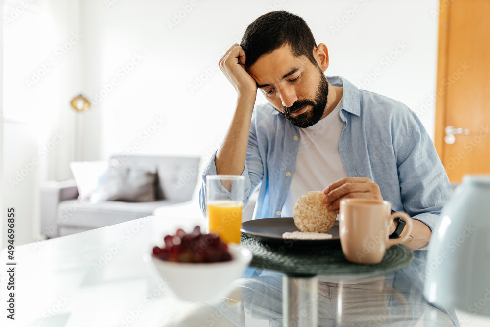 Depressed man at the table suffering from lack of appetite Depressed man at the table suffering from lack of appetite