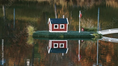 An idyllic scene in the town park in Sorreisa, Norway. Miniature houses with Norwegian flags in the middle of the lake reflected in the mirrorlike still water. Autumn foliage in the background. photo