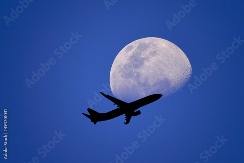 an airplane flying across a moon or Passenger plane - airliner passes near the moon. Explore new frontier. Space traveler concept