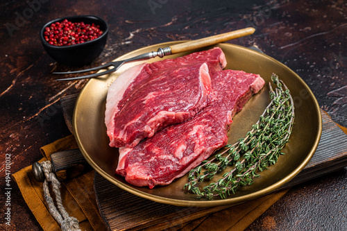 Freah Raw cap rump beef meat steak in a plate with thyme, top sirloin steak. Dark background. Top view