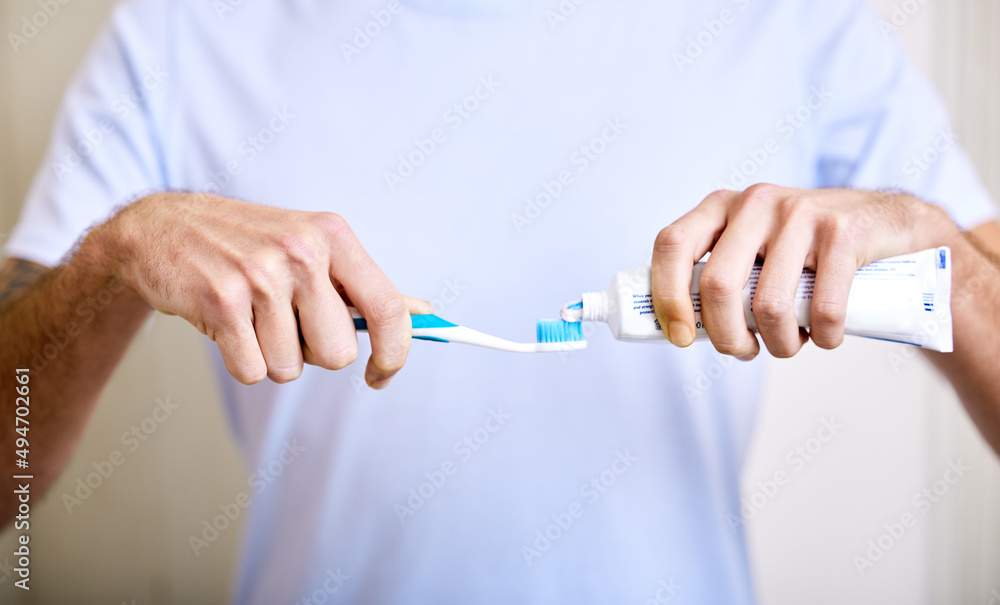 Brushing twice a day keeps the cavities away. Shot of a man applying toothpaste to his toothbrush. Brushing twice a day keeps the cavities away. Shot of a man applying toothpaste to his toothbrush.