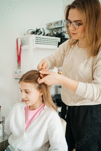 mom does her daughter hair a teenager uses a tablet