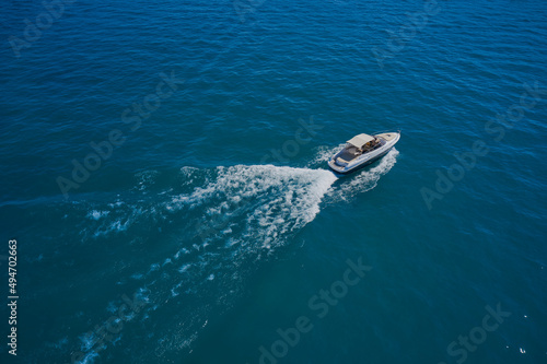 Speedboat moves fast on the water view from above. Big white boat with people in motion in the sea top view. Boat drone view. © Berg