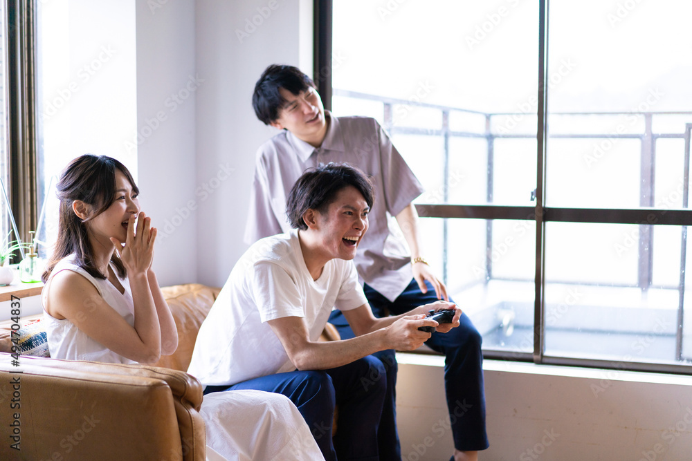 家でテレビゲームをする若い男女 家でテレビゲームをする若い男女