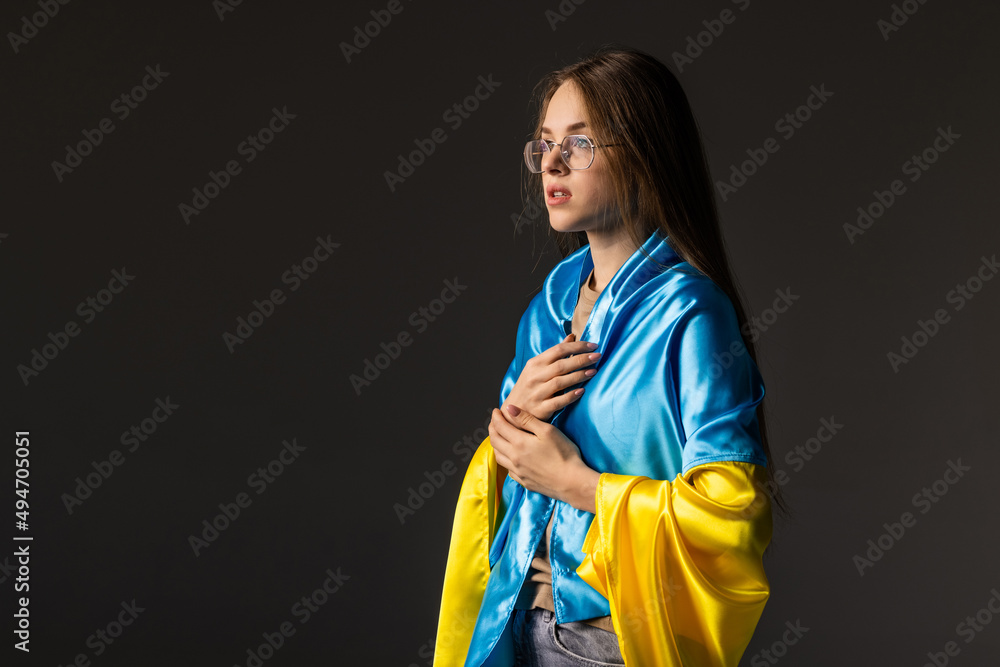 Sad young woman covered with Ukraine flag. Concept of standing with Ukrainian nation in war with Russia. Sad young woman covered with Ukraine flag. Concept of standing with Ukrainian nation in war with Russia.