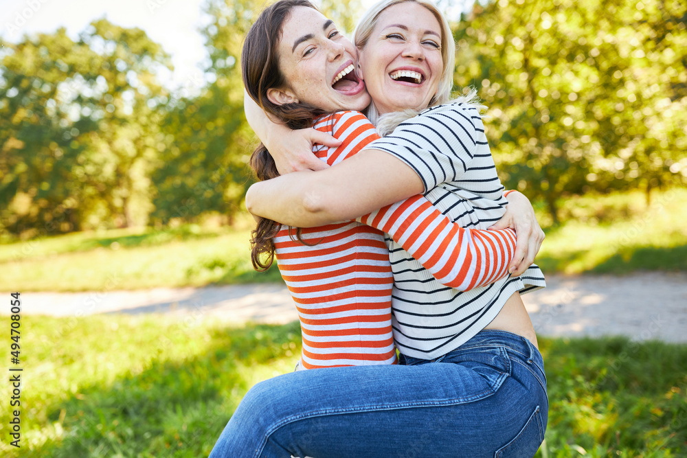 Two girlfriends hug each other, laughing happily Two girlfriends hug each other, laughing happily
