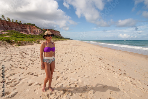 Lady standing at the beach known as Taipe with the colorful cliffs in the background near Arraial d’ Ajuda, Biaha, Brazil  photo