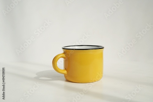 Yellow small coffee cup mockup for design presentation, white background with sunlight.