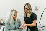 A nurse practitioner at a medical wellness spa showing an anti-aging skincare product to the patient or client