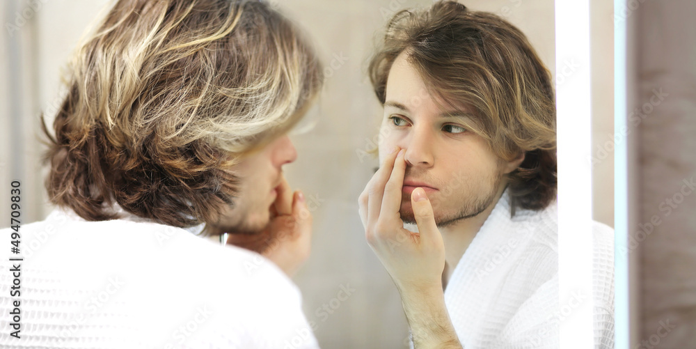 young man looking in the mirror,combing his hair,looking at problems on face. young man looking in the mirror,combing his hair,looking at problems on face.