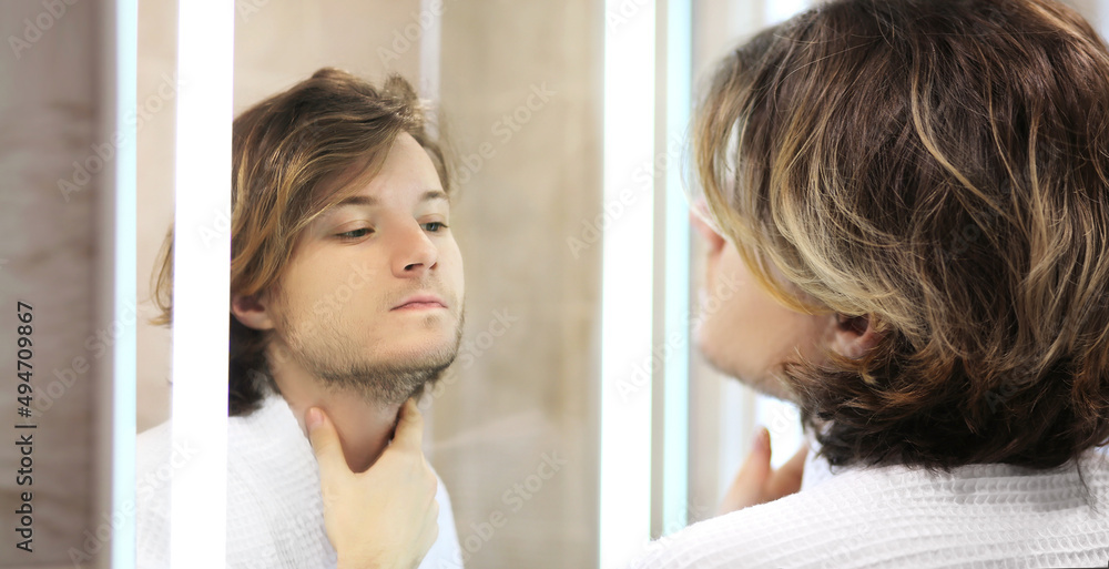young man looking in the mirror,combing his hair,looking at problems on face. young man looking in the mirror,combing his hair,looking at problems on face.