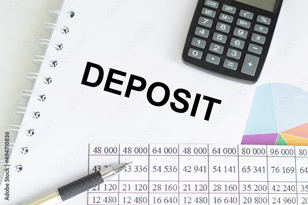 Deposit text on a notepad on a table with reports, calculator and pen, business and finance concept Deposit text on a notepad on a table with reports, calculator and pen, business and finance concept