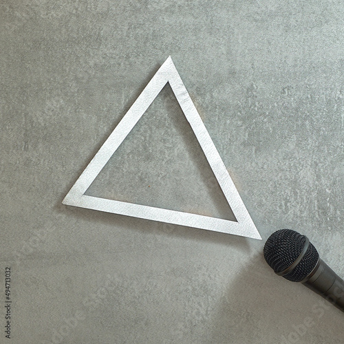 Simply. Microphone and silver triangle frame on gray concrete background. Text space. Top view. Minimal style. photo