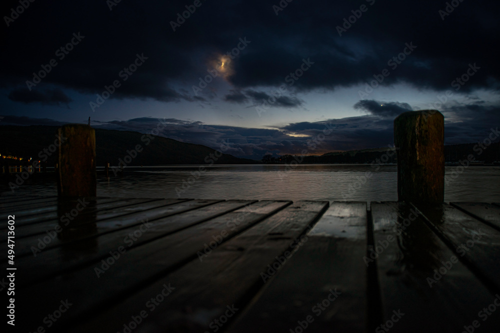 Coniston Lake at Night With moon and Reflactions on Water between two posts