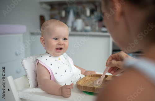 baby's first feeding, mom feeds a baby with a spoon