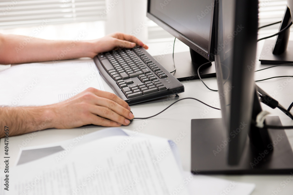 A person at a remote job. The programmer works on a computer. The hands of a man sitting behind a monitor with a keyboard. A person at a remote job. The programmer works on a computer. The hands of a man sitting behind a monitor with a keyboard.