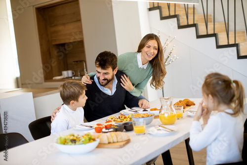 Young happy family talking while having breakfast at dining table