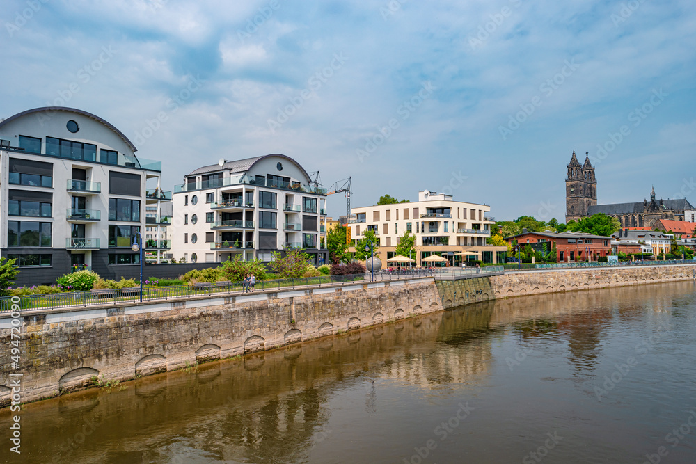 Obraz premium View over new modern houses at historical downtown in Magdeburg at Elbe river bank, Germany, at blue sky and sunny Spring day.