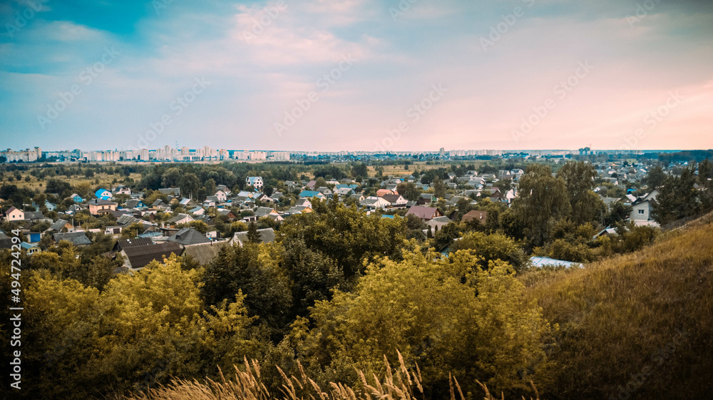 Fototapeta premium Evening sunset with a view of the village and the city in warm weather in the summer near the Dnieper boulevard in Mogilev, Belarus.