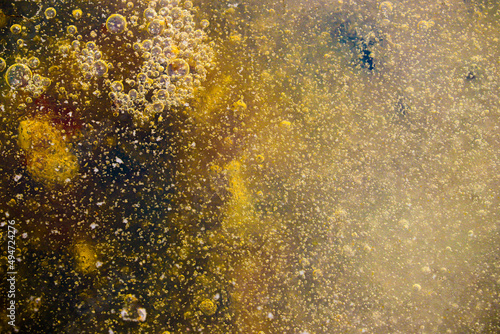 background of many bubbles frozen in ice on a yellow orange background © EVGENY