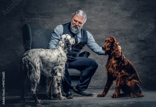 Elderly man with his purebred dogs sitting on armchair photo