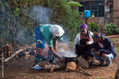 Older African Woman helping young teenage girls to prepare a pot of tea