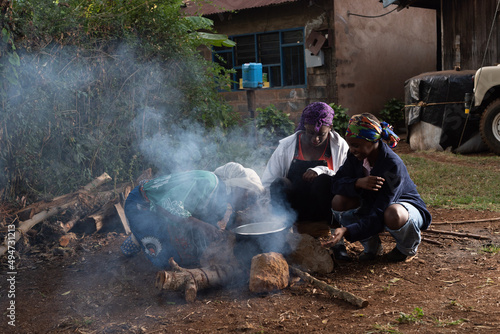 Older African Woman helping young teenage girls to  prepare a pot of tea photo