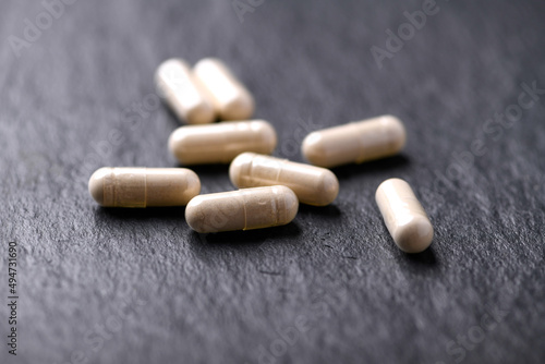 Maca capsules. Concept for a healthy dietary supplementation. Dark stone background. Soft focus. Close up.