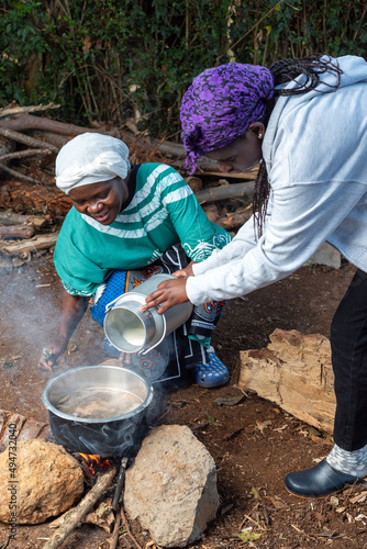 Young African teenager pouring fresh milk into pot 