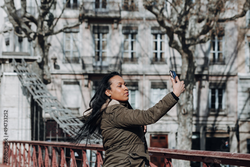 young woman using her phone to take picture over bridge in city of Lyon France