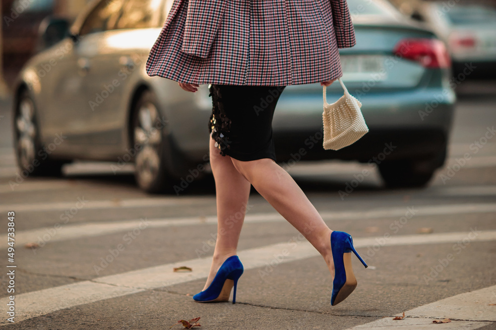 A woman in an oversized plaid jacket black midi skirt and blue