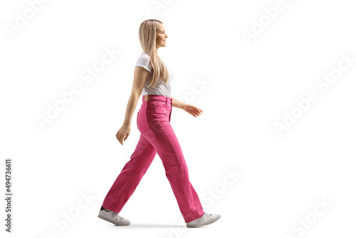 Full length profile shot of a young woman in pink jeans walking
