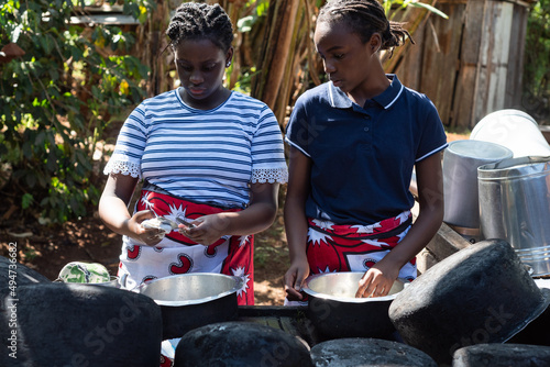 Young African Teenage sisters washing dishes at an outdoor area