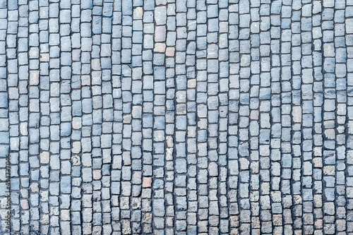 Cobblestone pavement texture background. Top view of stone road. Detail of granite sidewalk taken from above. Old street cobblestones for backdrop. Abstract vintage pavement with rough blocks.